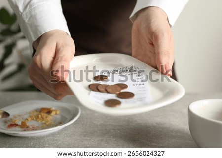 Waitress taking tips from grey table in cafe, closeup