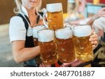 Waitress in traditional tracht holding and carrying multiple beer mugs in an Oktoberfest tent in Munich, germany