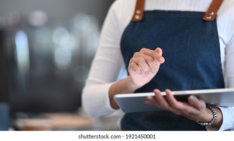 Waitress using digital tablet to receive orders from customers in modern coffee shop.