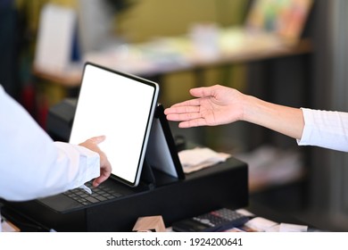 Waitress using tablet to receive orders from customers at counter service in coffee shop.