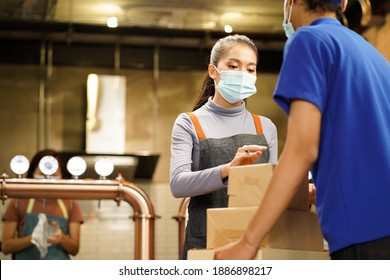 Waitress Wearing Mask Check The Box From Food Supply Delivery Man To Restaurant As New Normal While Coronavirus Or COVID-19 Outbreak