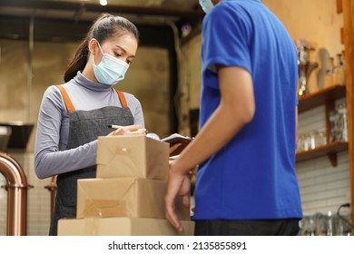 Waitress wearing mask check the box from food supply delivery man to restaurant pick up point and take away from online order as new normal while coronavirus or COVID-19 outbreak