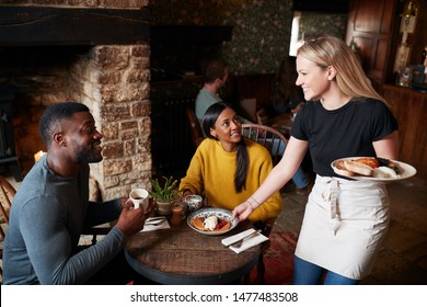Waitress Working In Traditional English Pub Serving Breakfast To Guests