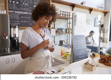 Waitress writing down an order at a coffee shop, close up