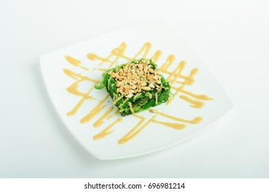 Wakame salad with peanuts and peanut sauce on a plate isolated on white background - Shutterstock ID 696981214