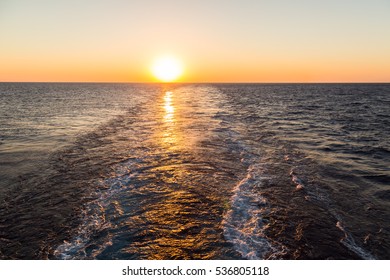 Wake Of The Cargo Ship On The Sea At Sunset Time.