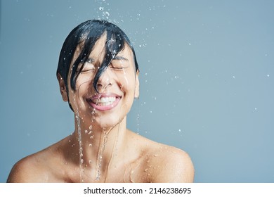Wake up to the refreshing sensation of water. Shot of a young woman having a refreshing shower against a blue background. - Shutterstock ID 2146238695