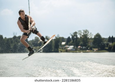 Wakeboarder surfing across a lake. A man wakeboards behind a boat. - Powered by Shutterstock