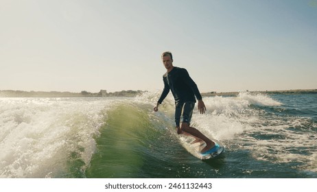 Wakeboarding. A wakeboarder glides on the water behind a boat. Skilled wakeboarding - Powered by Shutterstock