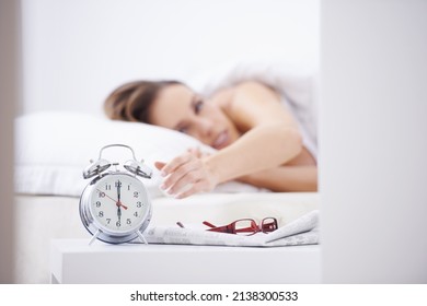 Waking From Her Slumber. A Young Woman Waking Up And Reaching Over To Her Alarm Clock.