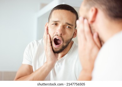 Waking Up Super Early Today Was So Helpful. Shot Of A Young Man Yawning While Looking At His Reflection In The Bathroom Mirror.