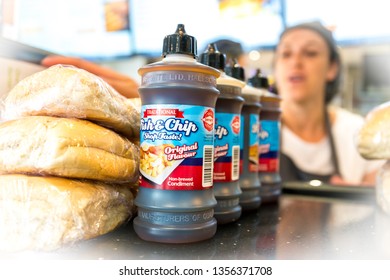 Wales, UK / April 1st 2019 : Serving Fish And Chips To Customers In Spotlessly Clean Fish And Chip Shop With Bottles Of Vinegar And Bread Rolls At The Front Of The Counter.