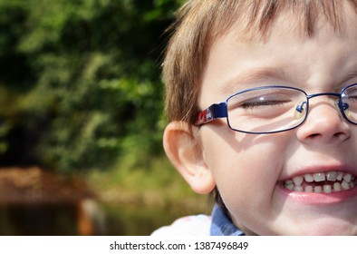 Wales, UK / May 3rd 2019 : Happy Little Boy With Huge Grin And Baby Milk Teeth And Spectacles Or Glasses Enjoying Playing In The Sunshine In Rural Area.