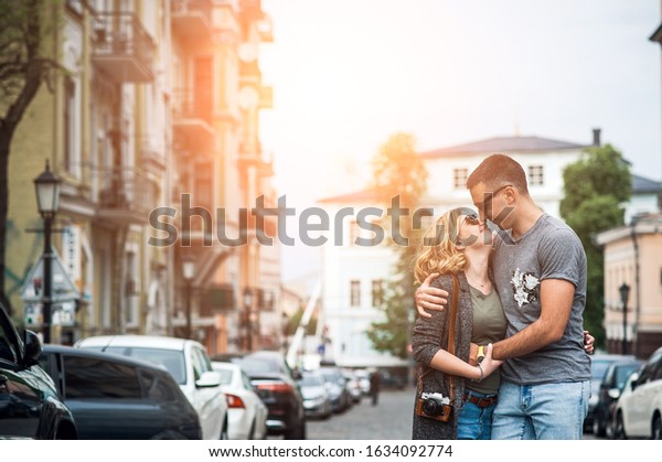 Walk around the city in the\
summer. Loving couple kisses on a narrow street among cars and\
houses