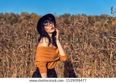 Similar – Beautiful young photographer woman wearing black clothes, sitting on the floor in countryside with her camera