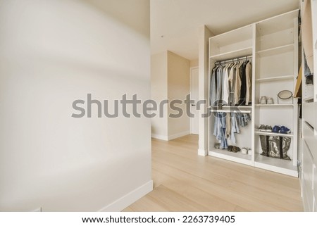 a walk - in closet with clothes hanging on the wall, and an open door that leads to another room
