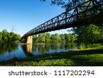 Walk way bridge with a reflection of a tree line on the Grand River in Ionia Michigan State Park in late spring