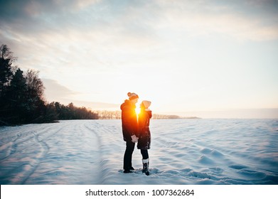 Walk in winter. Young people, a guy and a girl are kissing at sunset on a snow-covered field. Love story.
 - Powered by Shutterstock