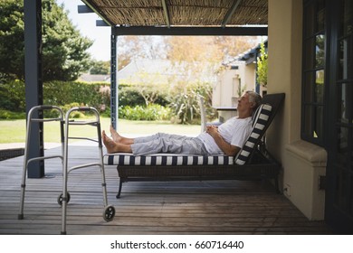 Walker By Senior Man Resting On Lounge Chair At Porch