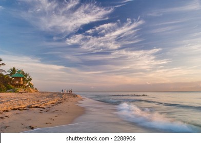 walkers and surf fishermen at dawn on the atlantic ocean beach, red rock reef, boca raton in south florida