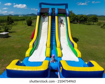 Walkerston, Queensland, Australia - January 2022: Children On A Giant Inflatable Water Slide In A Home Backyard