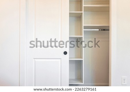 Walk-in closet shelves with sliding door in modern minimalist white style with bright light in staging model house apartment bedroom