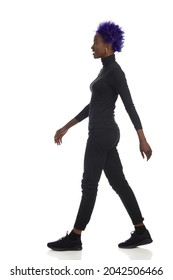 Walking African American Woman In Black Clothes And Sneakers. Side View. Full Length Studio Shot Isolated On White.