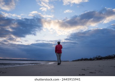 Walking alone in the beach with red jacket