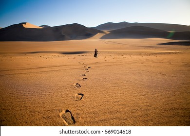 Walking alone in the desert with footsteps - Powered by Shutterstock
