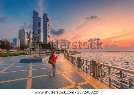 Walking along the Abu Dhabi Corniche promenade at sunset, enjoying the vibrant cityscape and serene waterfront views of modern skyscrapers