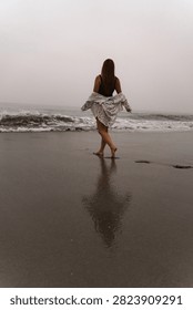 Walking along the beach with waves rolling in at sunset. A person walks on the wet sand of a beach as ocean waves crash nearby during sunset.