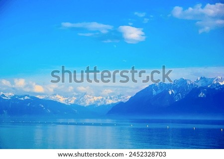 Walking along the promenade of Lake Geneva, against the backdrop of strong mountains under clear skies in Switzerland.