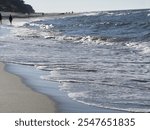 Walking along the seaside with sandy beach and waves