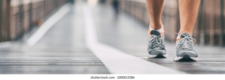 Walking exercise outside on city street banner. Running shoes closeup of man on outdoor walk training jogging. Active athlete on Brooklyn bridge, New York City lifestyle. Outdoor fitness panoramic.