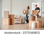 Walking forward with boxes. Young couple with dog are moving to new home.