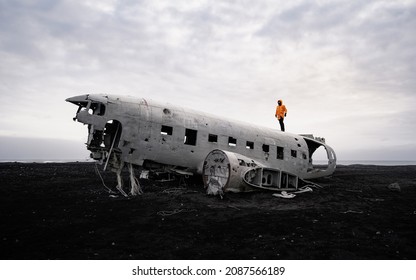 Walking man on the old crashed plane abandoned on Solheimasandur beach near Vik in Iceland. Landscape with popular tourist attraction in Iceland. Exciting excursion to the sights view in winter