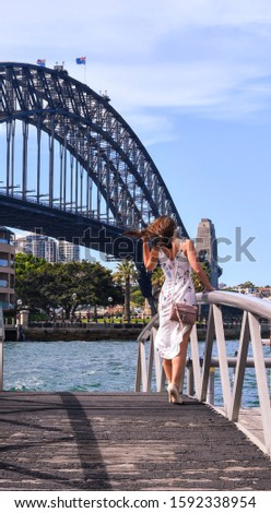 Happy woman looking at camera with Harbor Bridge in the background, in Sydney city, Australia.