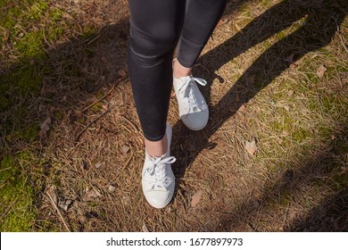 
Walking on a path in a pine forest. 
White women's sneakers. 