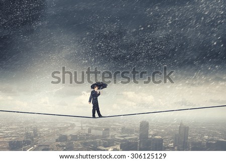Walking on rope businessman with black umbrella 