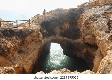 Walking path over a hole in a limestone cliff on the Seven Hanging Valleys Trail on a winter day in Algarve, Portugal.