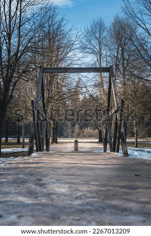 Walking path in the park with a wooden bridge over the stream in winter, Ljubljana