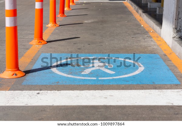 Walking path for people with orange barriers. Road\
with signs of people on the blue floor. Accessible Sign for person\
on the street floor.