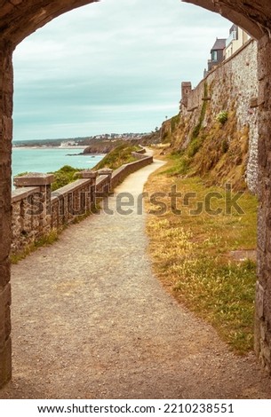 walking path, trail through arched stone door, on a France beach, autumn landscape, Granville