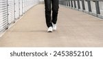 Walking pedestrian bridge in city. Feet in white sneakers in motion.