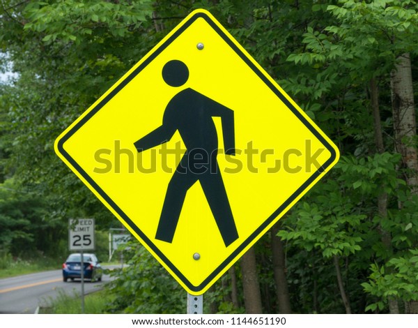 Walking or Pedestrian Sign near a road with a
car on background