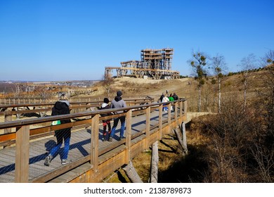 Walking People On  Wooden Footbridge. Wooden Lookout Tower At Kurza Gora In Background. Kurzetnik, Warmia And Masuria, Poland