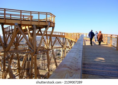 Walking People On  Wooden Footbridge. Wooden Lookout Tower At Kurza Gora In Background. Kurzetnik, Warmia And Masuria, Poland