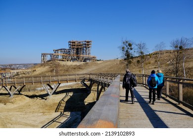 Walking People On  Wooden Footbridge. Wooden Lookout Tower At Kurza Gora In Background. Kurzetnik, Warmia And Masuria, Poland