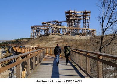 Walking People On  Wooden Footbridge. Wooden Lookout Tower At Kurza Gora In Background. Kurzetnik, Warmia And Masuria, Poland