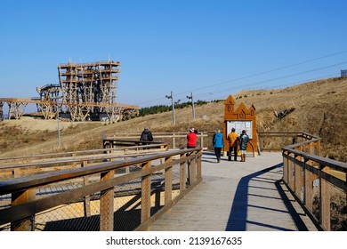 Walking People On  Wooden Footbridge. Wooden Lookout Tower At Kurza Gora In Background. Kurzetnik, Warmia And Masuria, Poland